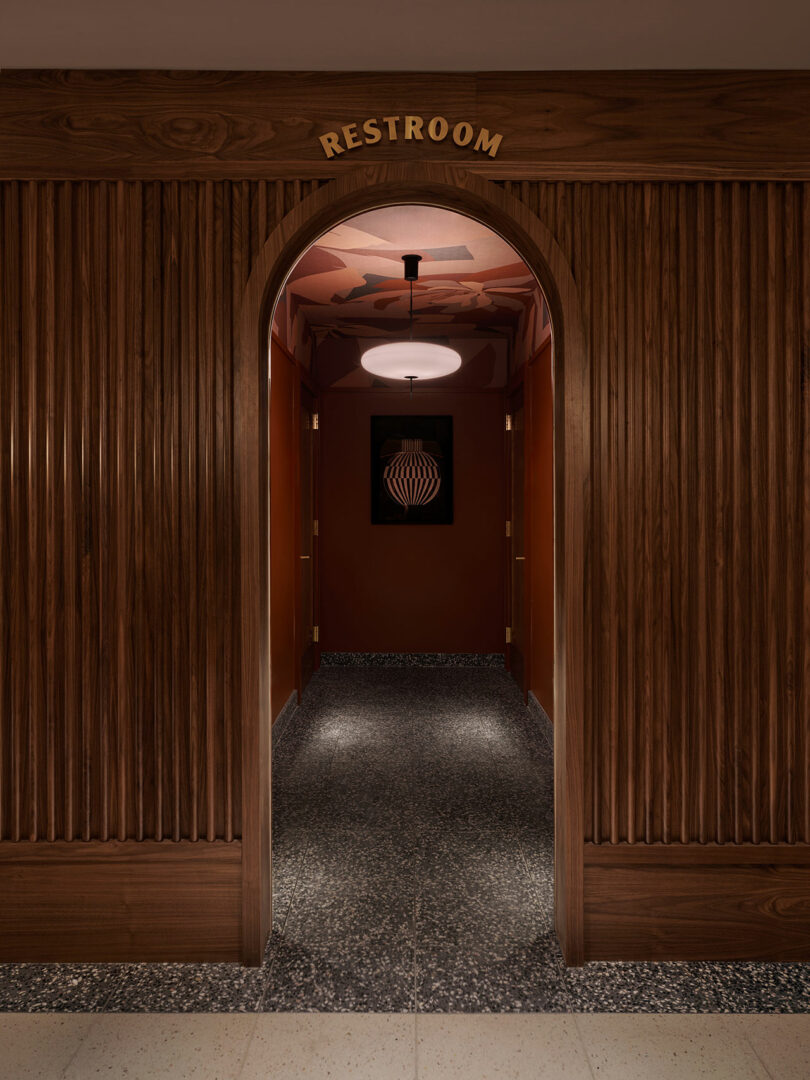 A hallway with wood paneling and an arched entrance labeled 