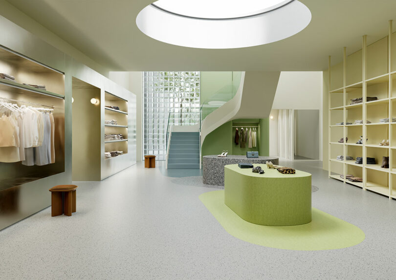 Minimalist clothing store interior with light-colored Tarkett shelves, a central green display table, curved staircase, and a large round skylight above. Clothing and shoes are neatly arranged on the shelves.