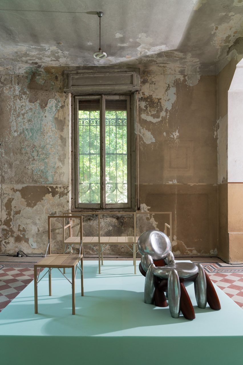 Photo of exhibits in the House of Creatures exhibition showing two chairs, one light, slim and straight, the other a monstruous creation made of two bulbous chairs squished into one another