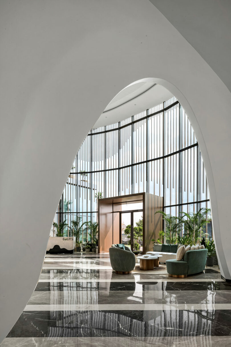 Modern lobby with large floor-to-ceiling windows, striped vertical panels, marble floors, green chairs, gold tables, and indoor plants creates a confluence of elegance and contemporary design.