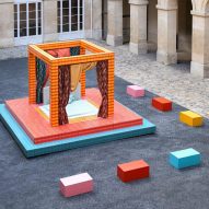 A photograph of an installation depicting a four poster bed in colours of blue, pink and orange, situated in a square of the Hôtel de la Marine.