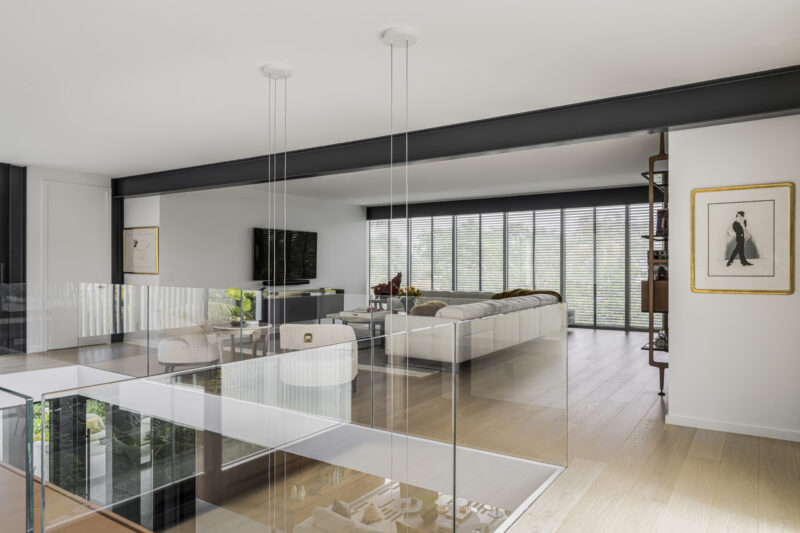Modern interior reminiscent of the Paul Rudolph Biggs Residence, with large glass sliding doors, white vertical slats, indoor plants, and sunlight on a terrazzo floor.