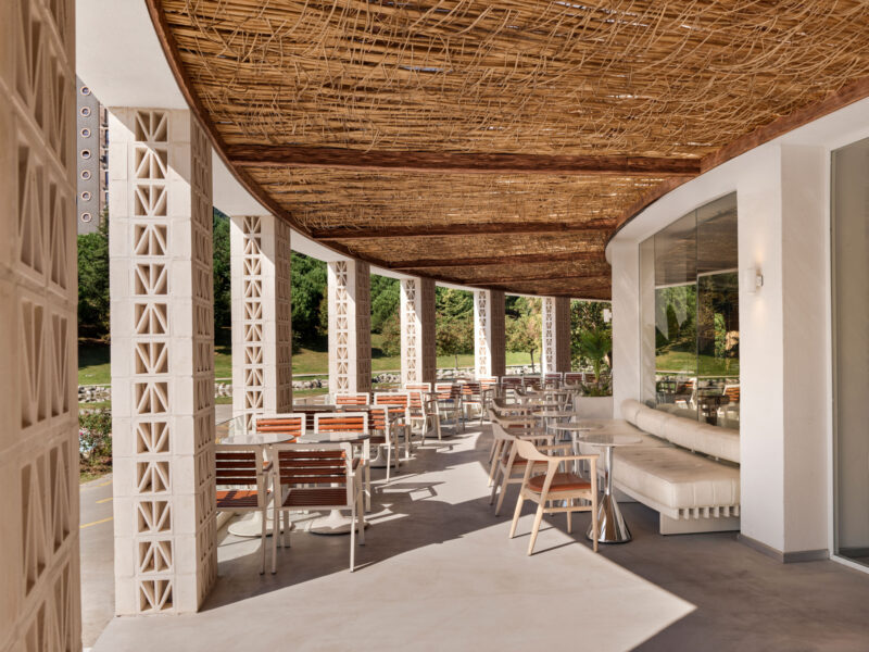 Local People cafe outdoor patio with tables and chairs under a woven wood canopy, supported by decorative concrete columns.
