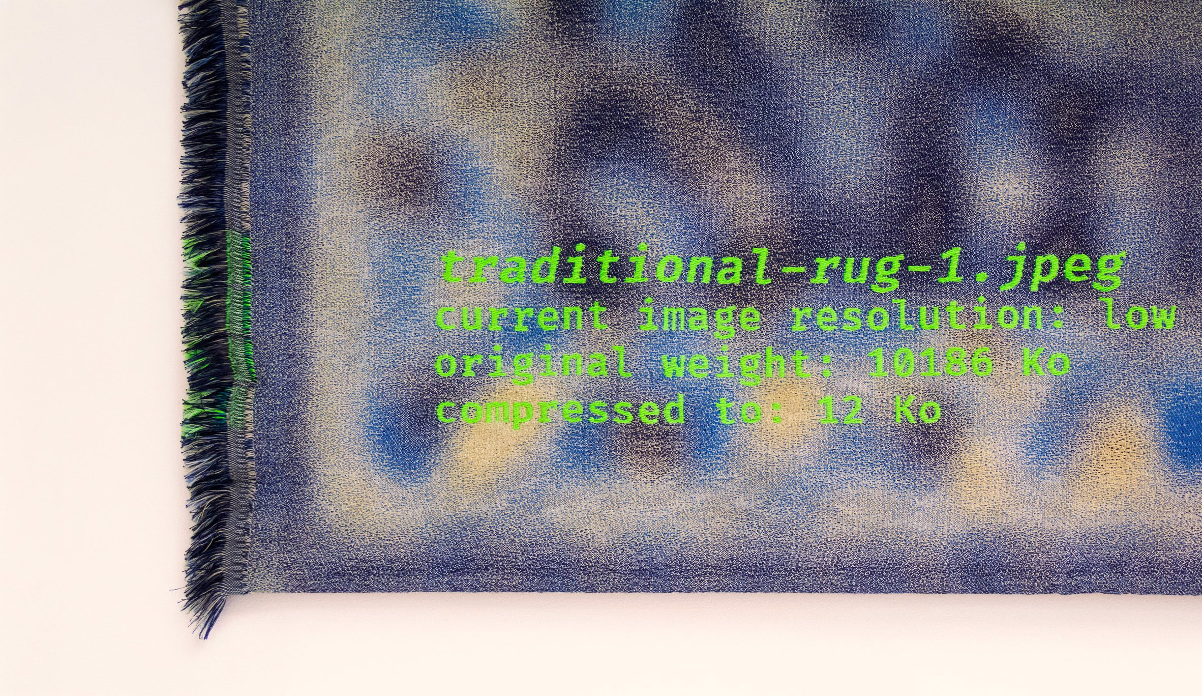Detail photo of corner of a rug with writing embroidered onto it