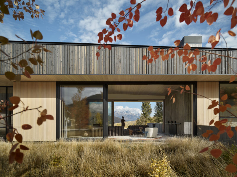 Modern home with large glass sliding doors opening to a living area, framing a mountain view beyond.